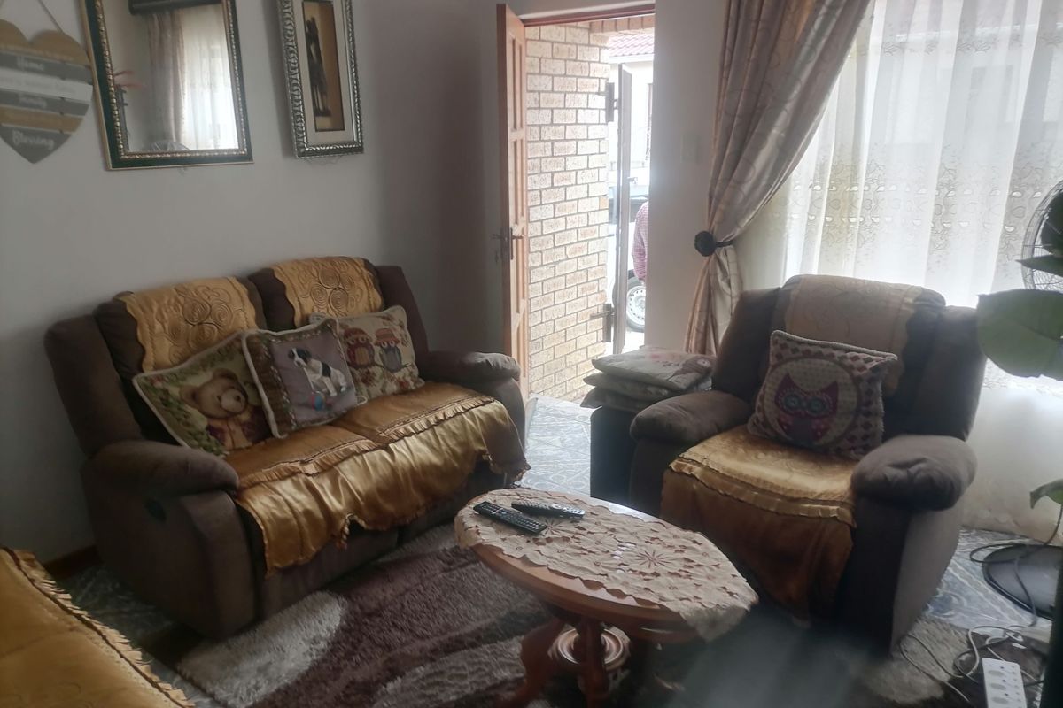 A cozy living room area featuring a direct entrance door and natural light through a window with curtains.