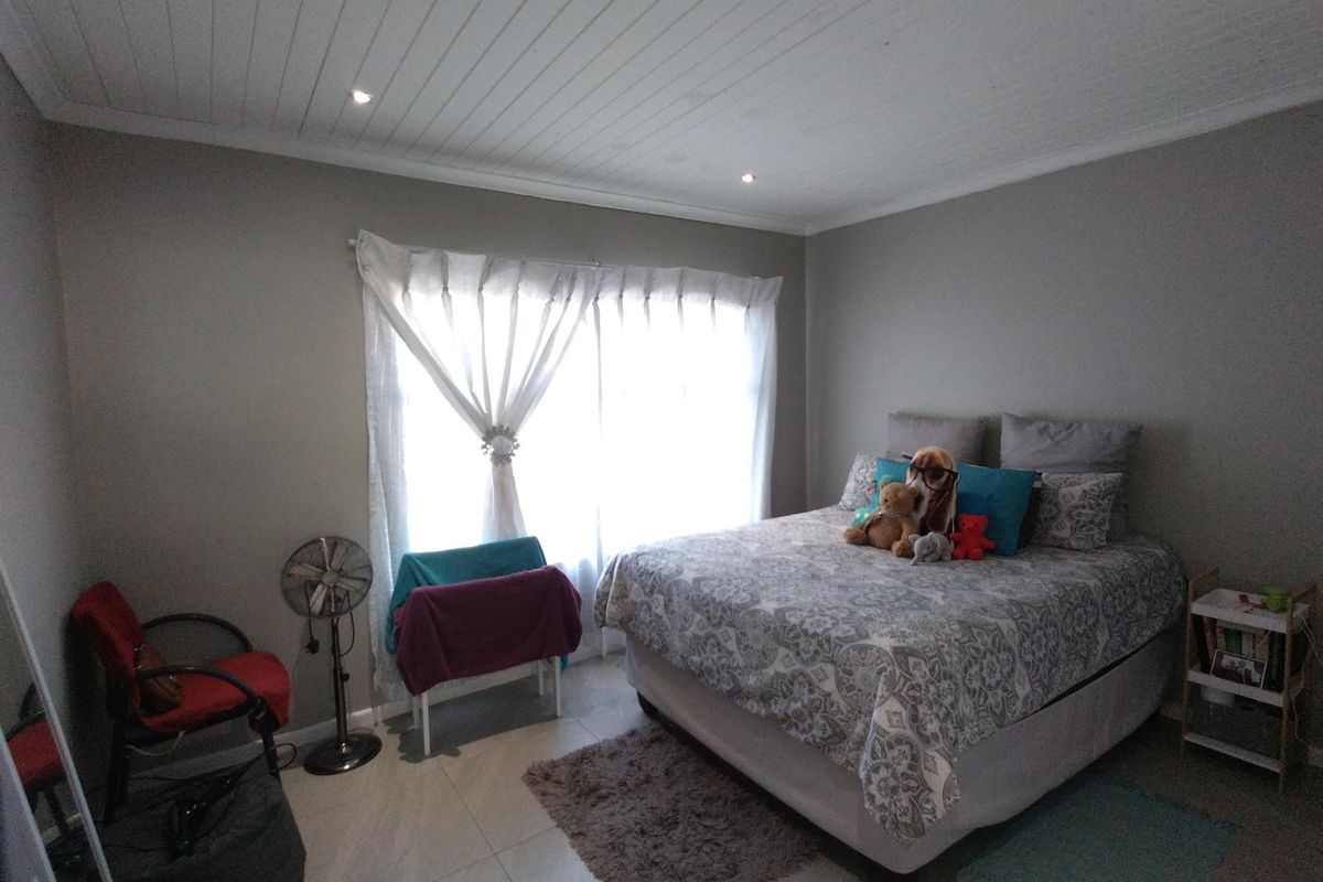 A bedroom featuring tiled flooring, a white tongue-and-groove ceiling with recessed lighting, and a large window with sheer curtains.