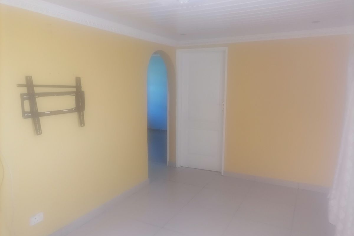 An empty room featuring tiled flooring, a white paneled ceiling with crown molding, and an arched doorway leading to an adjacent space.