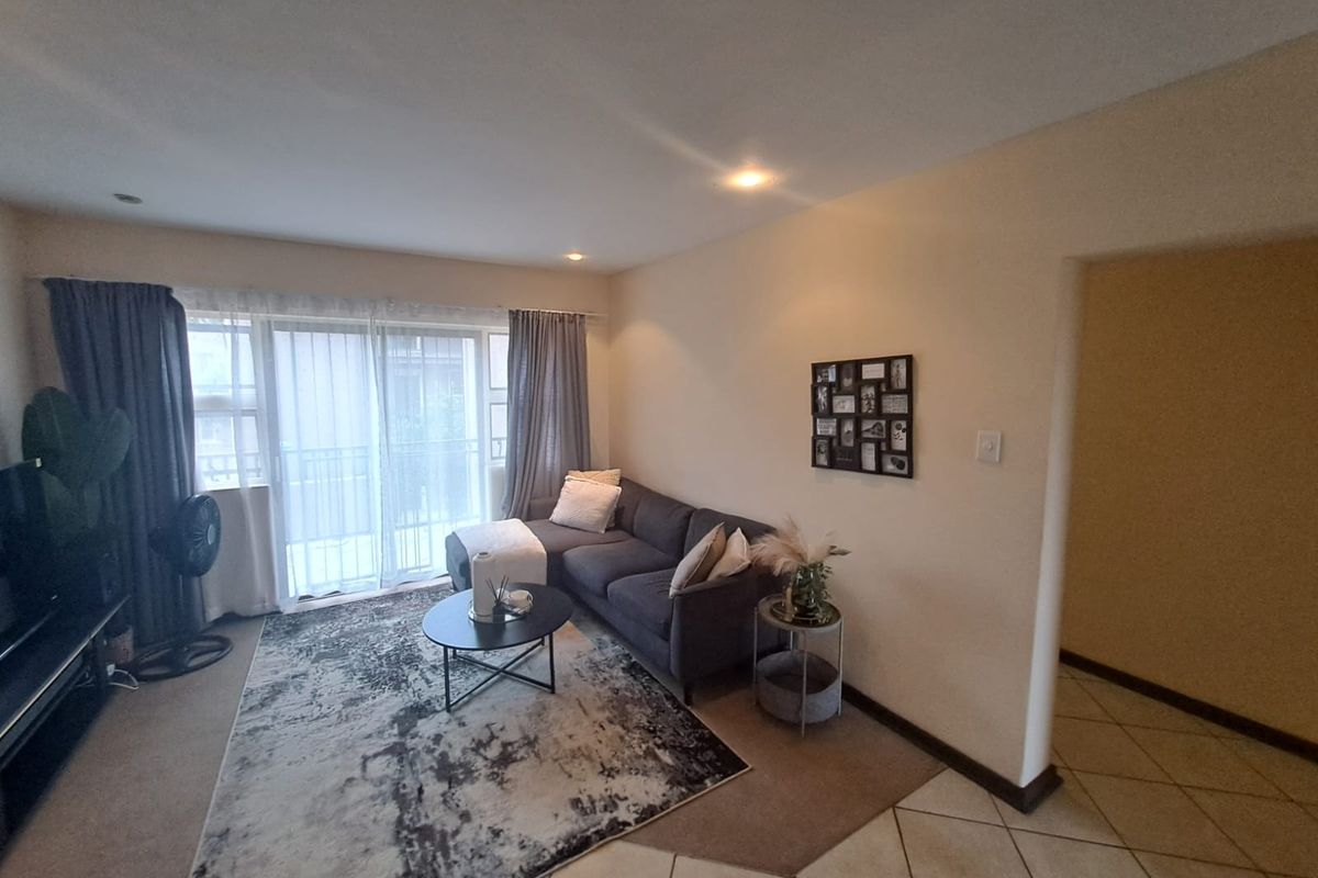 A comfortable living room featuring sliding glass doors that open to a balcony, providing natural light and access to outdoor space.