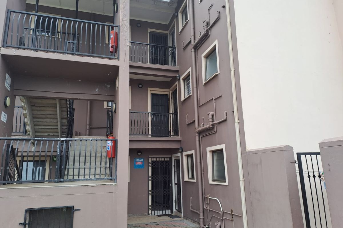 Exterior view of an apartment building complex featuring multi-level balconies, security gates, and external stairwell access.