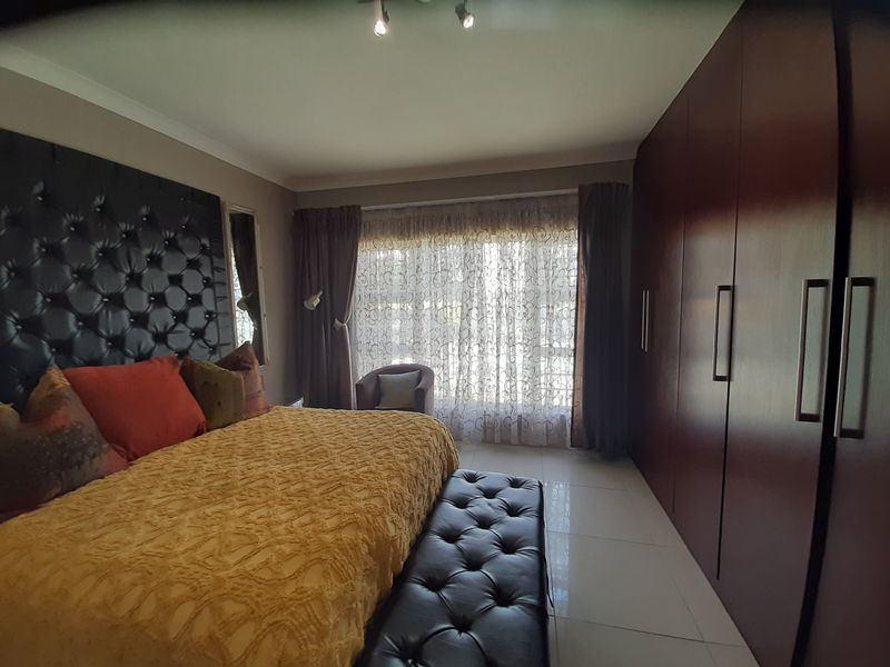 Spacious bedroom featuring large built-in cupboards, tiled flooring, and modern ceiling spotlights, offering a comfortable and functional living space.