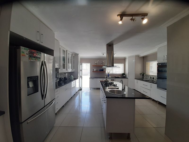 Modern kitchen featuring a central island with a gas hob, built-in oven, ample cabinetry, and polished tiled flooring.