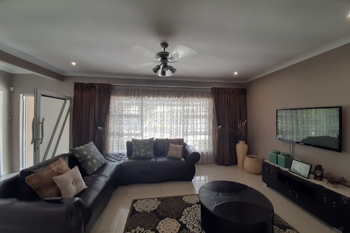 A comfortable living room featuring tiled flooring, recessed lighting, a ceiling fan, and large windows with curtains.