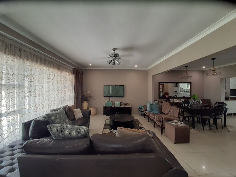 Spacious open-plan living and dining area featuring neutral wall tones, tiled flooring, and modern ceiling lighting fixtures.