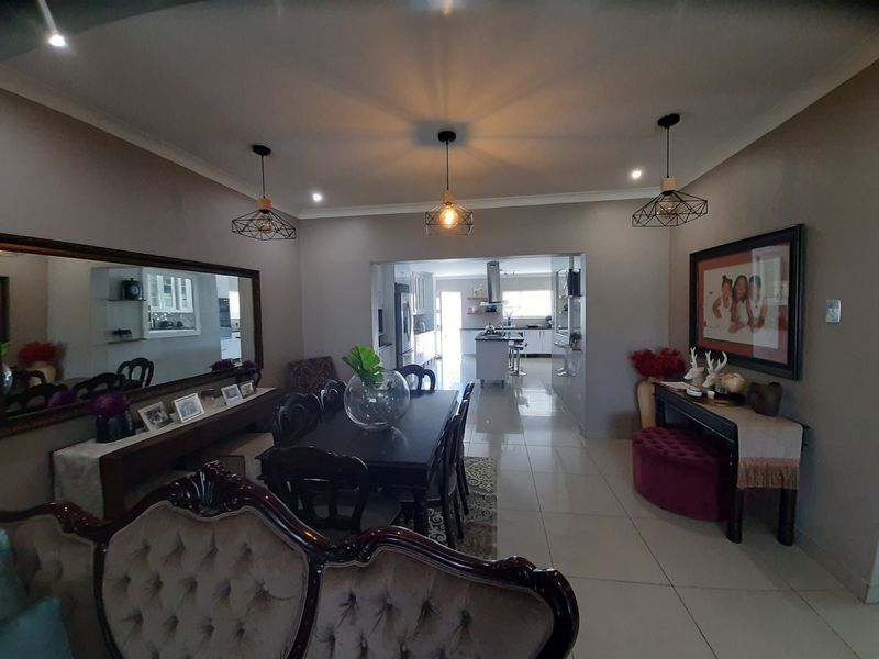 Spacious open-plan living and dining area featuring polished floor tiles, modern pendant lighting, and a seamless transition into the contemporary kitchen space.