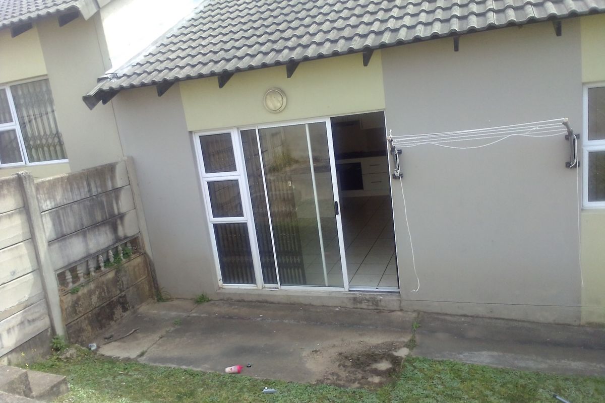 Rear view of the apartment featuring a concrete patio area, sliding glass door access, and a wall-mounted retractable clothesline.