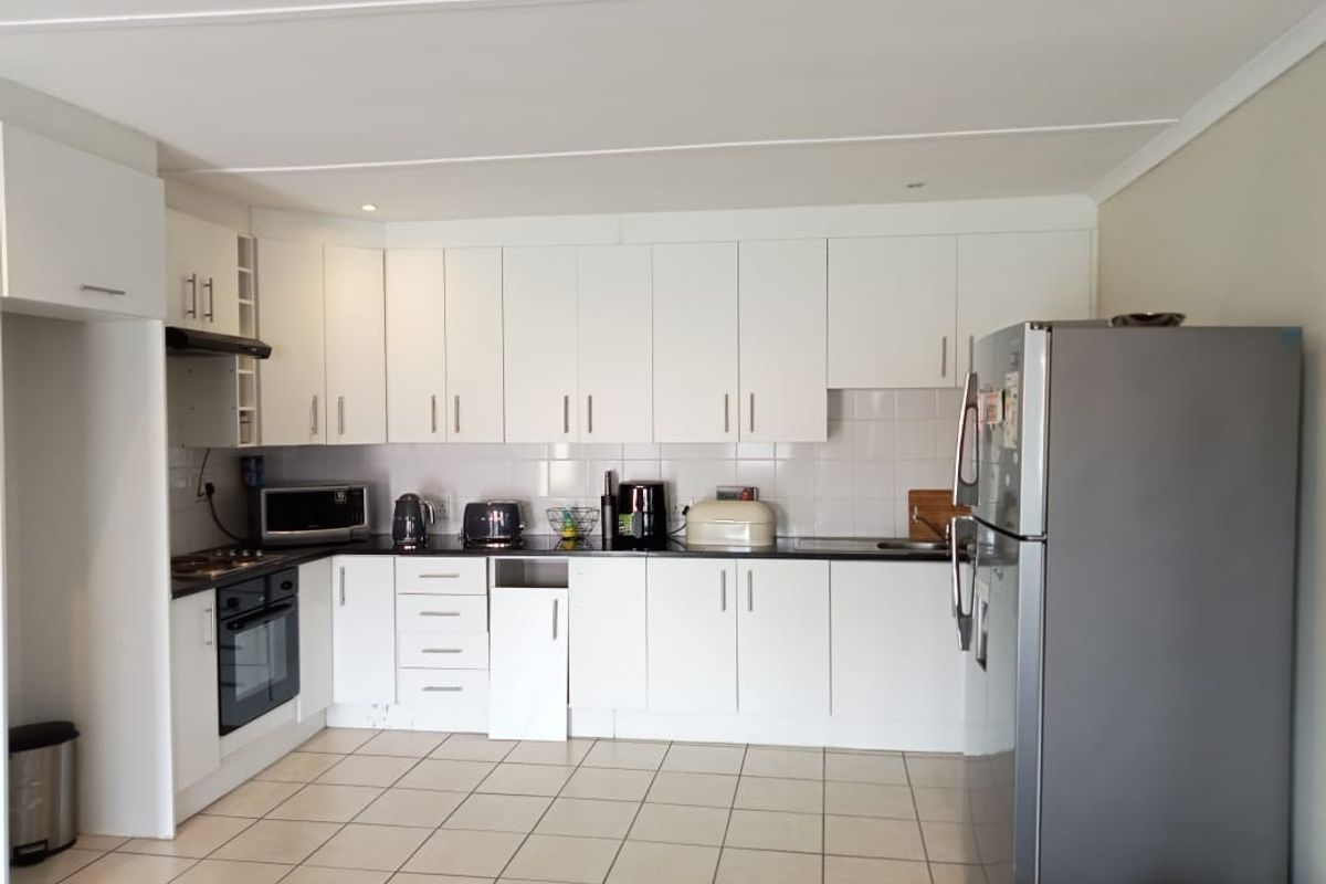 A functional kitchen featuring white cabinetry, tiled flooring, a built-in oven, and a hob, providing a clean and practical workspace.