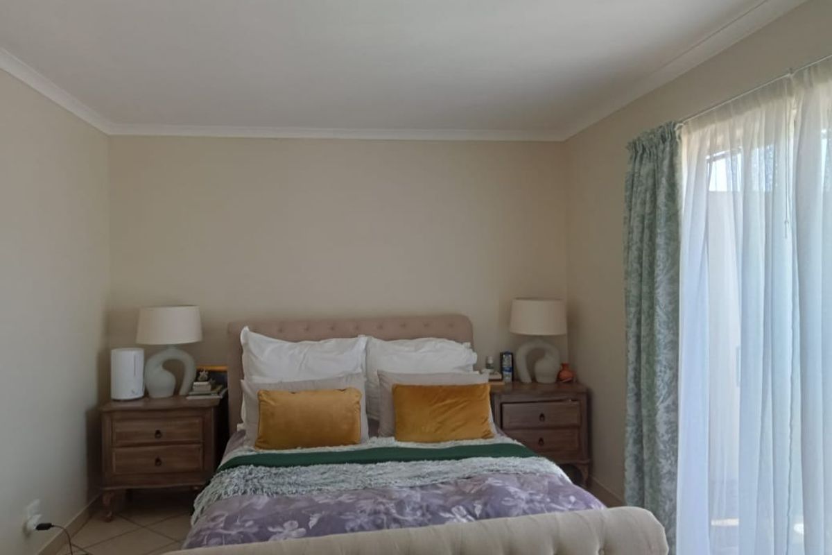 A well-lit bedroom featuring neutral wall tones, tiled flooring, and a sliding door providing access to the exterior.