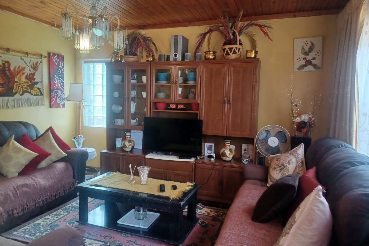 A traditional living room featuring a timber-clad ceiling, built-in wooden cabinetry, and a glass block window detail.