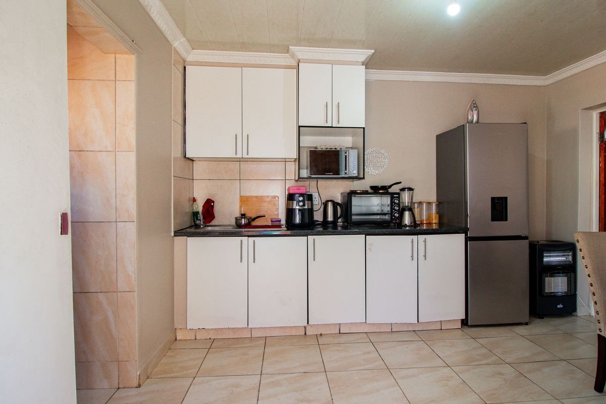 A functional kitchen area featuring white cabinetry, tiled flooring, and a dedicated space for a refrigerator.