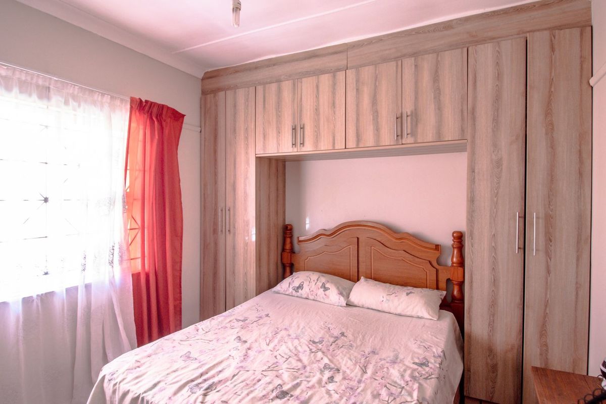 A bedroom featuring built-in wooden cabinetry with overhead storage and a window with natural light.
