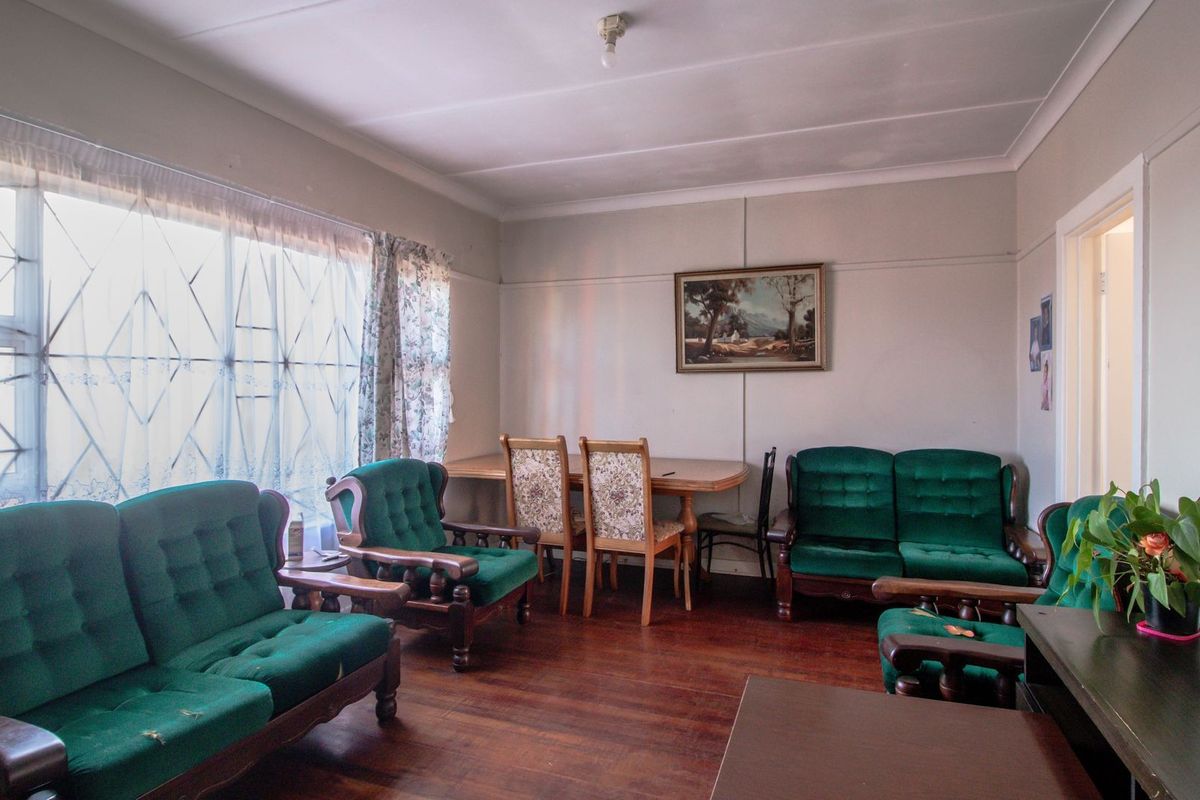 A spacious living and dining area featuring original timber flooring, large windows, and neutral wall finishes.