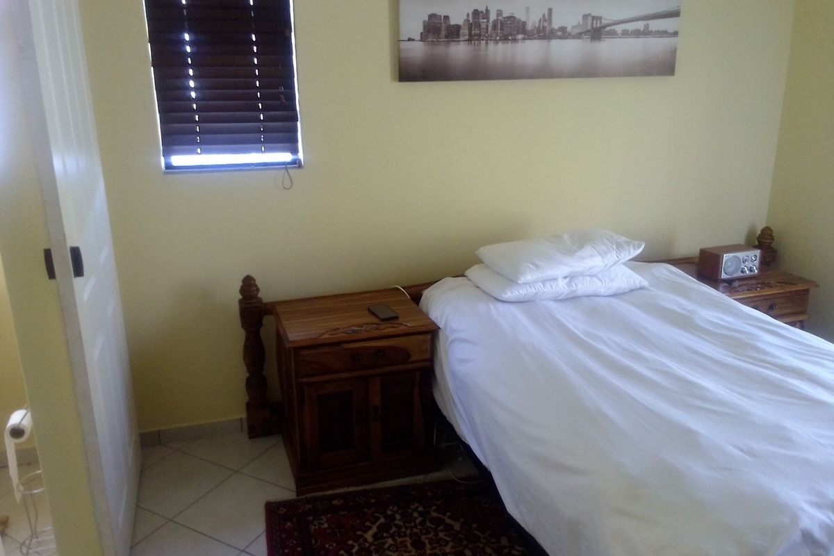 A bedroom featuring tiled flooring and a window with fitted blinds.