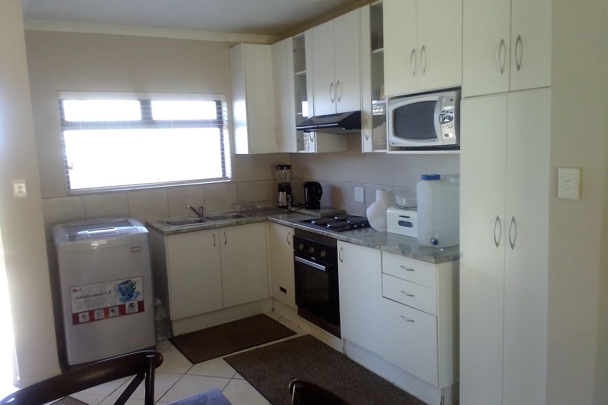 Functional kitchen featuring white cabinetry, built-in oven, hob, extractor fan, and integrated sink with tiled splashback and tiled flooring.