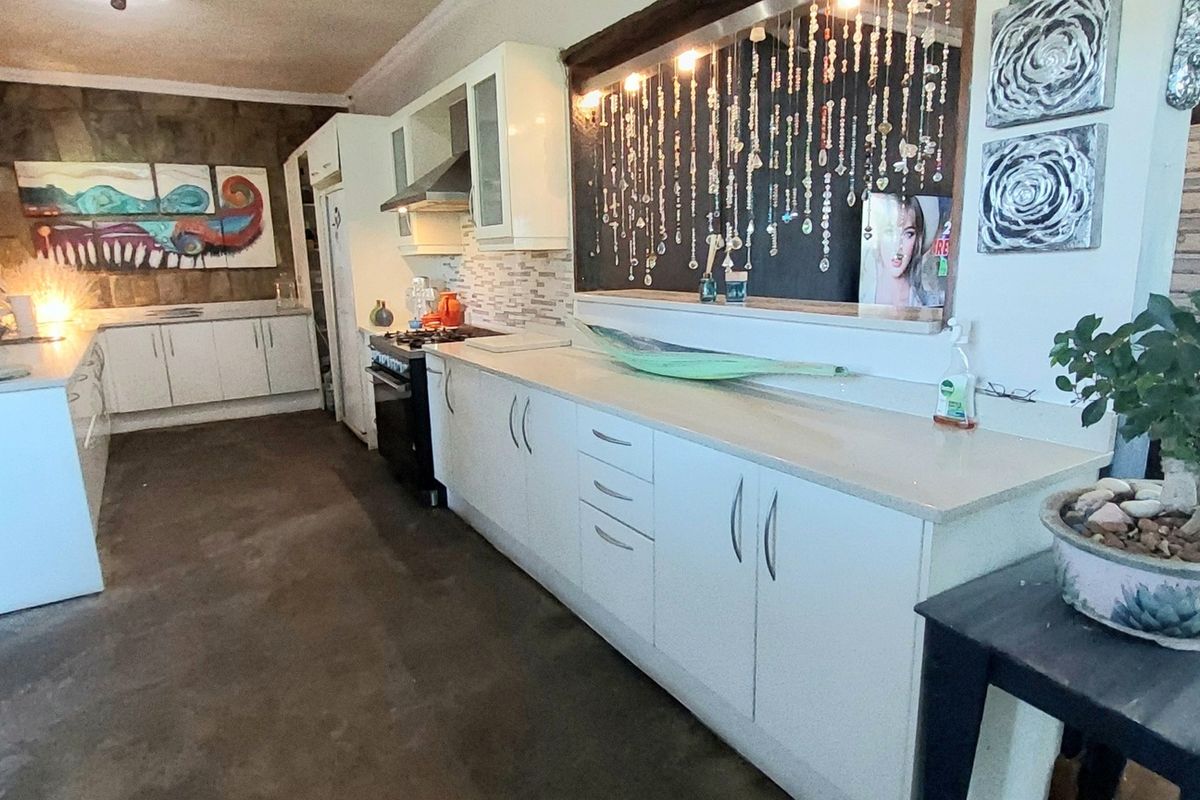 A functional kitchen featuring white cabinetry, stone-look countertops, a built-in oven, and a stainless steel extractor fan.