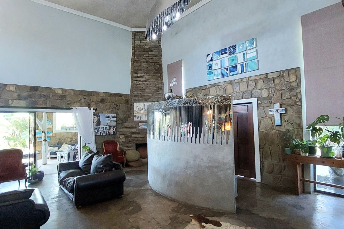 Spacious living area featuring a double-volume ceiling, stone-clad feature wall, fireplace, and a unique curved partition wall with a mezzanine level above.