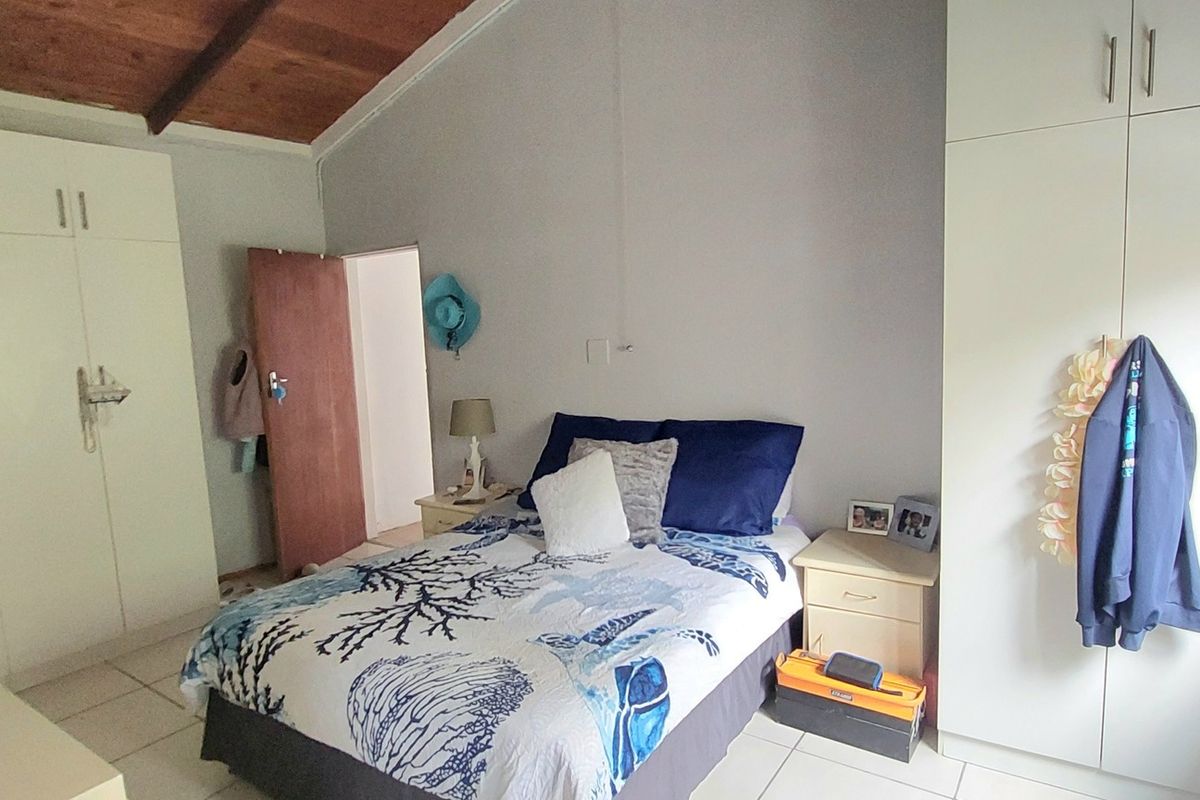 A bedroom featuring a vaulted timber ceiling, tiled flooring, and extensive built-in cabinetry providing ample storage space.