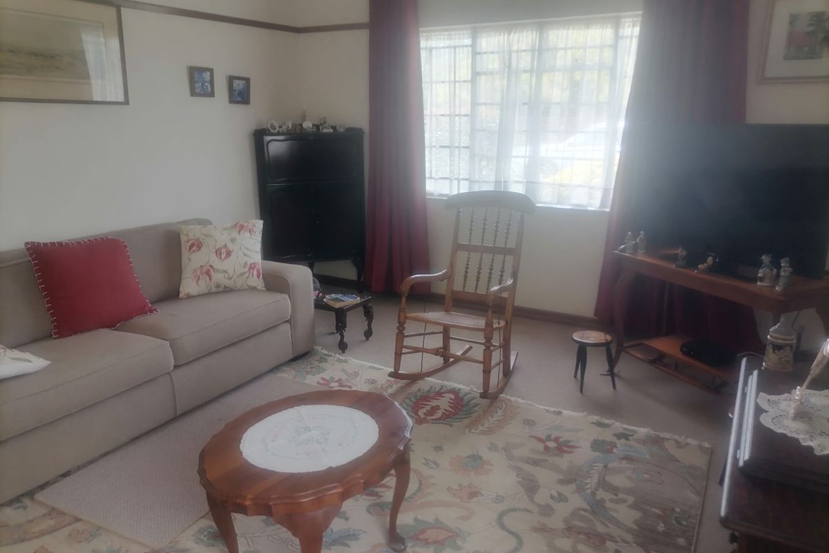 A cozy living room featuring traditional architectural details, including a picture rail and large window with natural light.