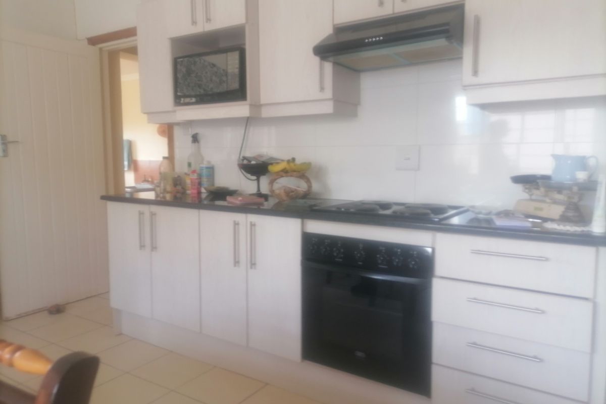 A functional kitchen featuring white cabinetry, a built-in oven, a gas hob, an extractor fan, and tiled flooring.