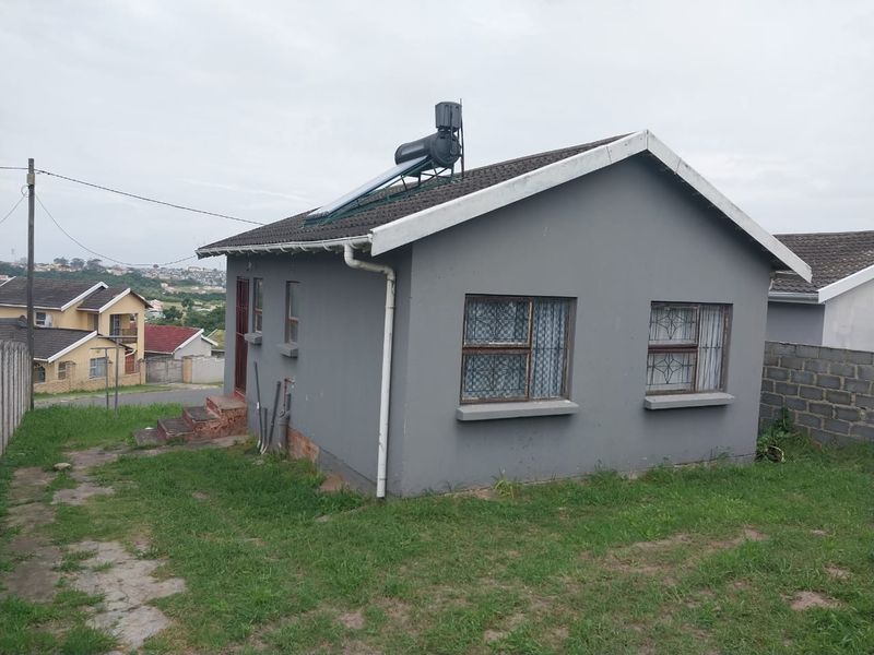 Rear view of a detached house featuring a solar water heating system, tiled roof, and security bars on the windows.