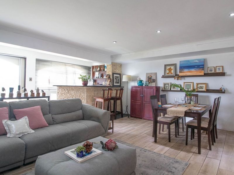 Spacious open-plan living and dining area featuring tiled flooring, recessed lighting, and a built-in bar counter with stone cladding detail.