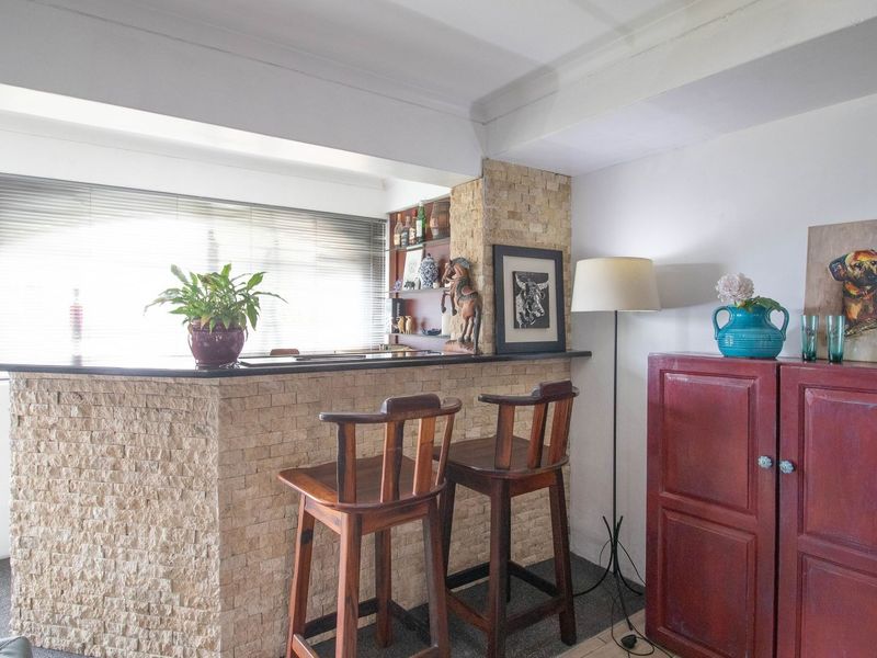 A dedicated bar area featuring a stone-clad counter and integrated shelving, providing a functional space for entertaining.