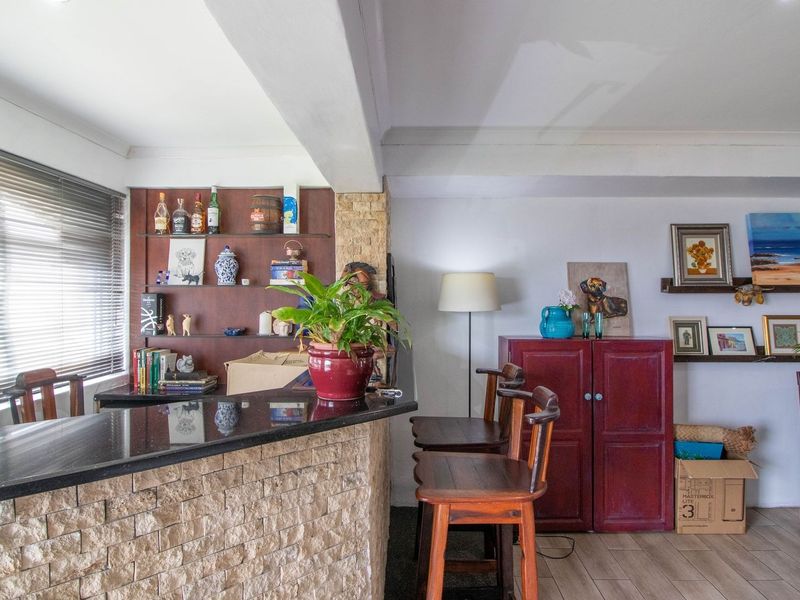 Open-plan living area featuring a stone-clad breakfast bar with granite countertop, built-in shelving, and tiled flooring, creating a functional and versatile space.
