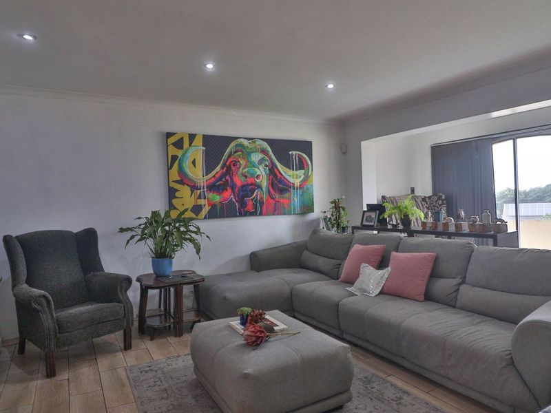 A well-lit living room featuring tiled flooring, recessed downlights, and a large sliding glass door providing access to the exterior.