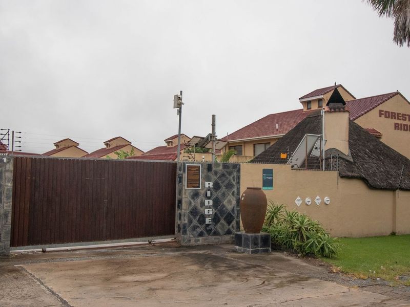 Front entrance gate and security perimeter of the Forest Ridge townhouse complex, featuring stone-clad pillars and integrated security systems.