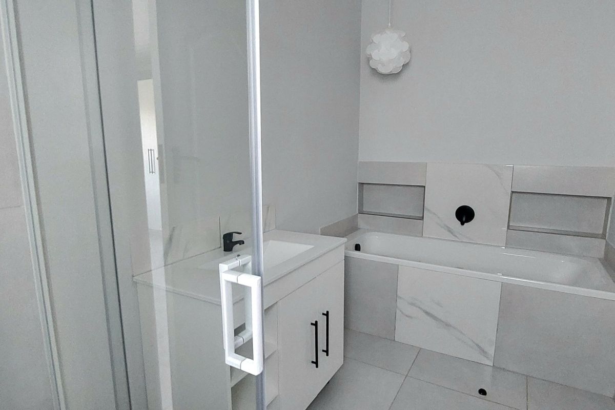 Modern bathroom featuring a built-in bathtub with tiled surround, recessed wall niches, and a contemporary vanity unit with a basin.