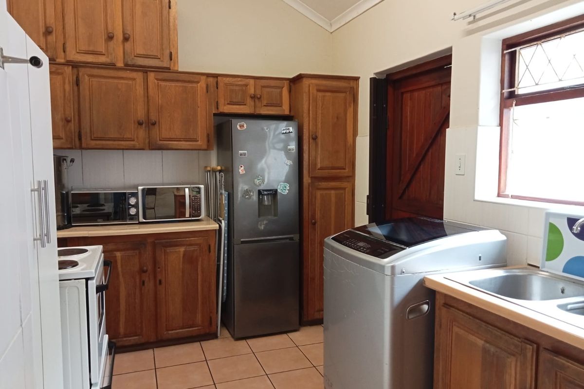 A functional kitchen featuring wooden cabinetry, tiled flooring, and a vaulted ceiling, providing a practical workspace with integrated sink and storage.
