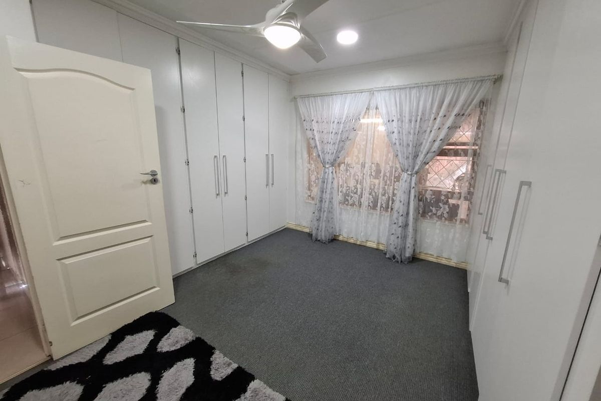 A bedroom featuring extensive built-in cabinetry, a ceiling fan, and carpeted flooring, offering ample storage space.