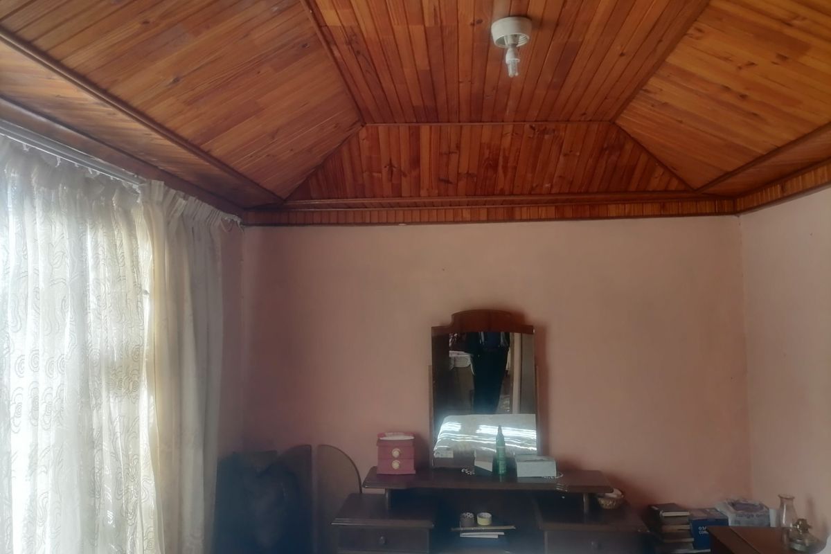 A bedroom featuring a traditional timber tongue and groove ceiling and neutral wall finishes, offering a blank canvas for modernization.