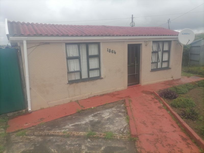Front elevation of a single-story residential house featuring a tiled roof, aluminium window frames, and a concrete pathway leading to the entrance.
