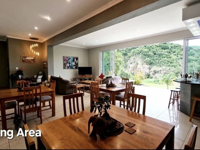 Spacious open-plan living and dining area featuring large sliding glass doors that open to a scenic outdoor view and a built-in breakfast bar.