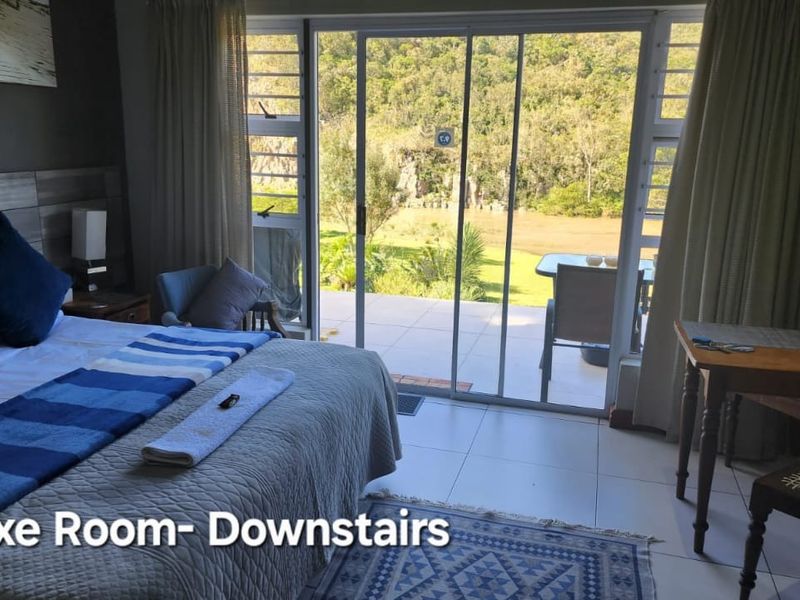 A well-lit bedroom featuring large sliding glass doors that provide direct access to an outdoor patio area with scenic garden views.