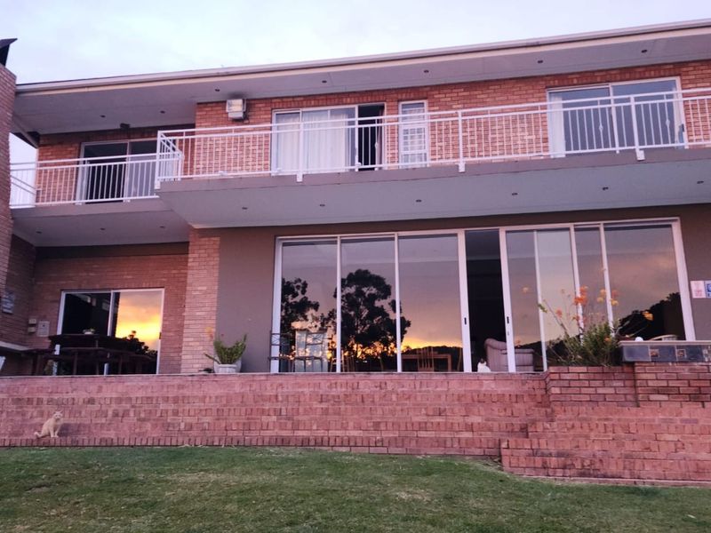 Rear view of a two-story brick guest house featuring a spacious patio, large sliding glass doors, and an upper-level balcony with metal railings.