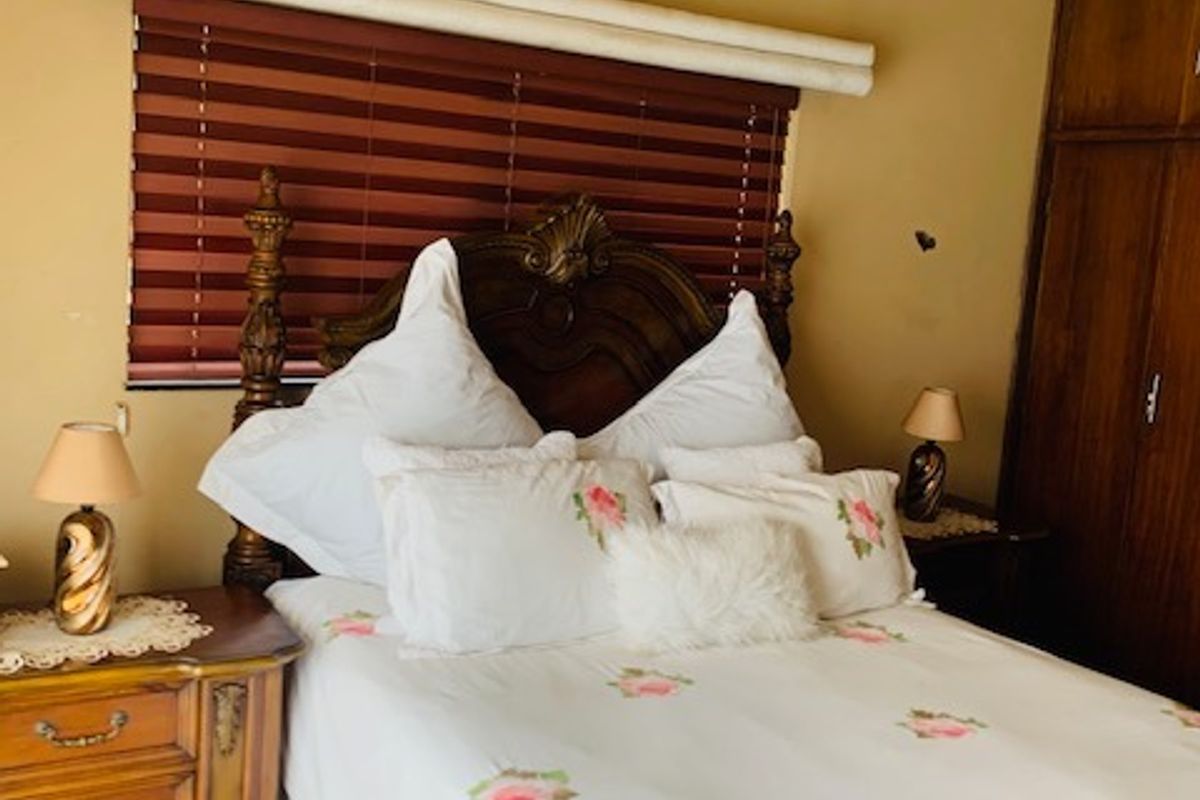 A bedroom featuring built-in wooden cabinetry, a wall-mounted air conditioning unit, and window blinds.