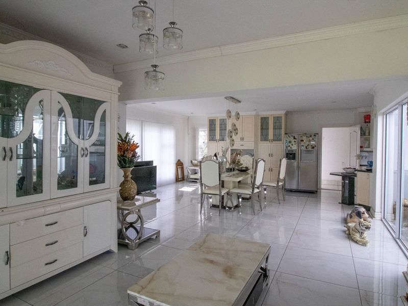 Spacious open-plan living and dining area featuring polished tile flooring, recessed lighting, and large sliding glass doors providing access to the exterior.