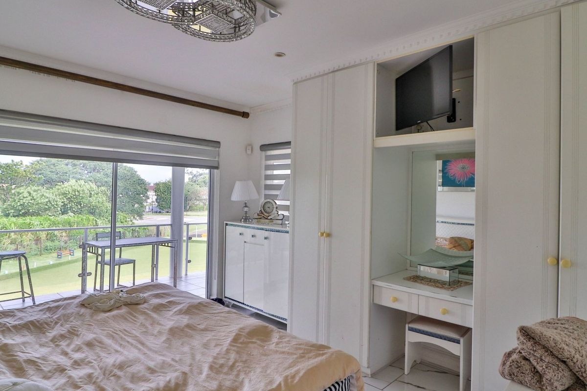Spacious bedroom featuring built-in cupboards, a vanity area, and large sliding doors opening onto a private balcony with scenic views.