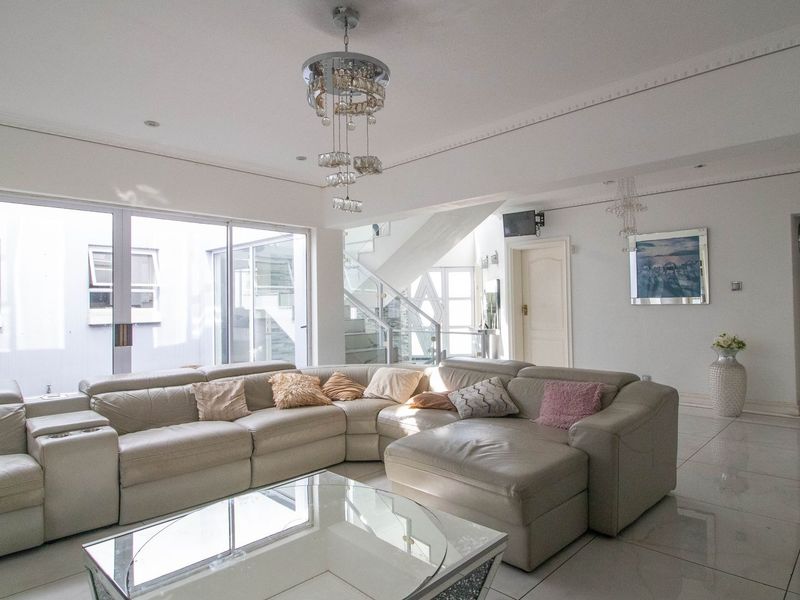 Spacious living area featuring large sliding glass doors, polished tile flooring, and a modern staircase with a glass balustrade.