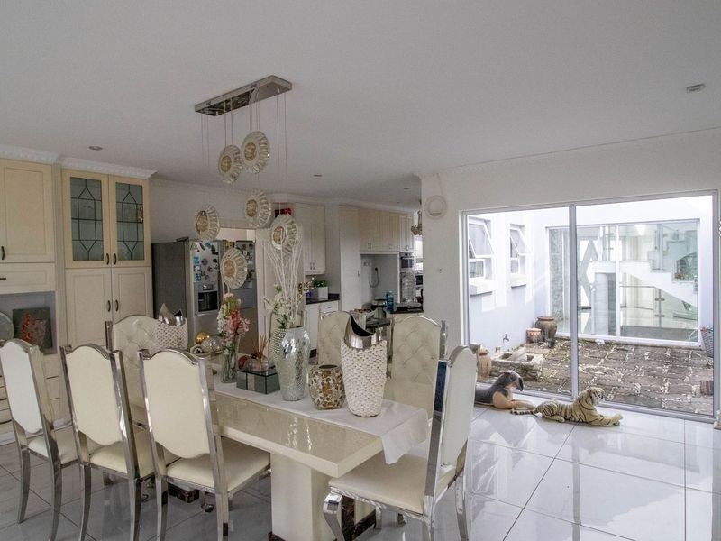 Open-plan dining and kitchen area featuring tiled floors, built-in cabinetry, and large sliding glass doors providing access to an outdoor courtyard.