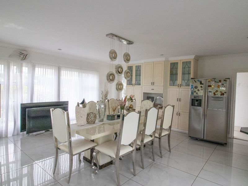 Spacious open-plan dining area featuring polished tiled flooring, extensive built-in cabinetry, and integrated display storage, creating a bright and functional living space.