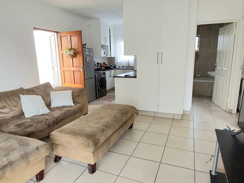 Open-plan living area featuring tiled flooring, integrated kitchen cabinetry, and built-in storage, with direct access to the kitchen and bathroom.
