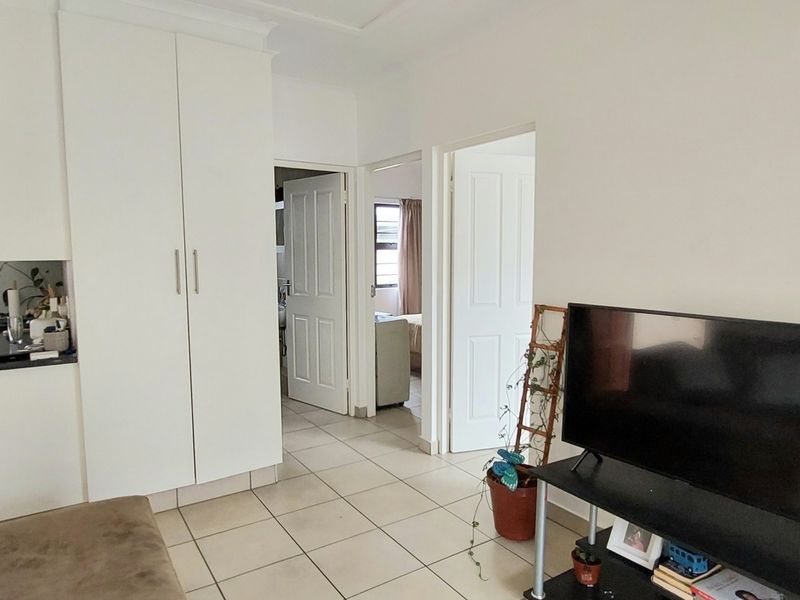 Open plan living area featuring tiled flooring, built-in storage cupboards, and a functional kitchen space with direct access to adjacent rooms.