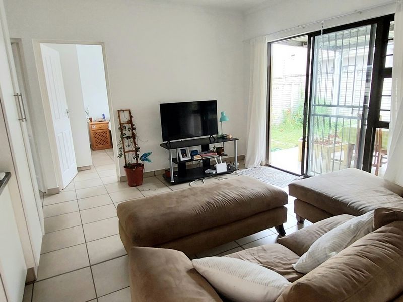 Open-plan living area featuring tiled flooring, kitchen cabinetry with granite countertops, and a sliding glass door providing access to the rear patio.