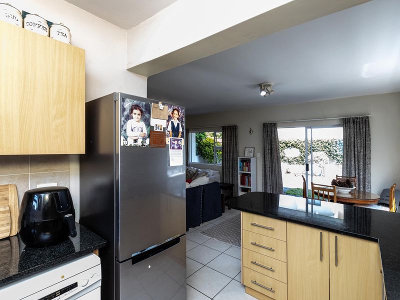 Open-plan kitchen and living area featuring granite countertops, light wood cabinetry, and direct access to the rear garden through sliding glass doors.