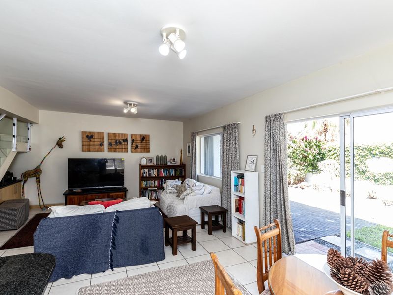 Open-plan living area featuring tiled flooring, a staircase, and sliding glass doors providing direct access to the rear patio and garden.