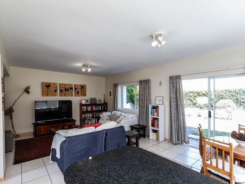 Open plan living and dining area featuring tiled floors, granite kitchen counter, and sliding glass doors providing access to the rear garden.